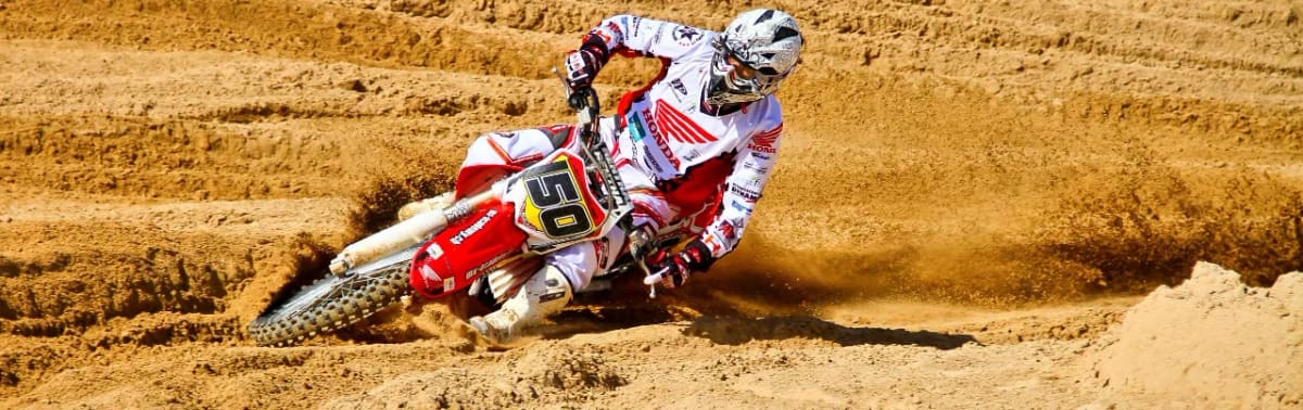 Motocross rider on a Honda dirt bike leaning into a sandy corner at MX-Academy