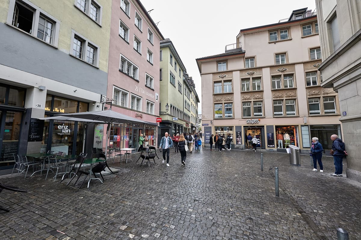 Cobbled Niederdorfstrasse in Zurich Old Town with shops and café tables